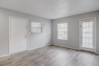 an empty bedroom with a door and two windows